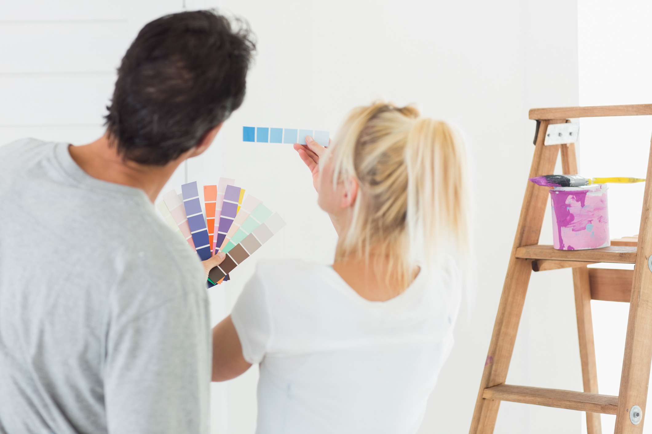 A couple choosing the paint colour for a room.