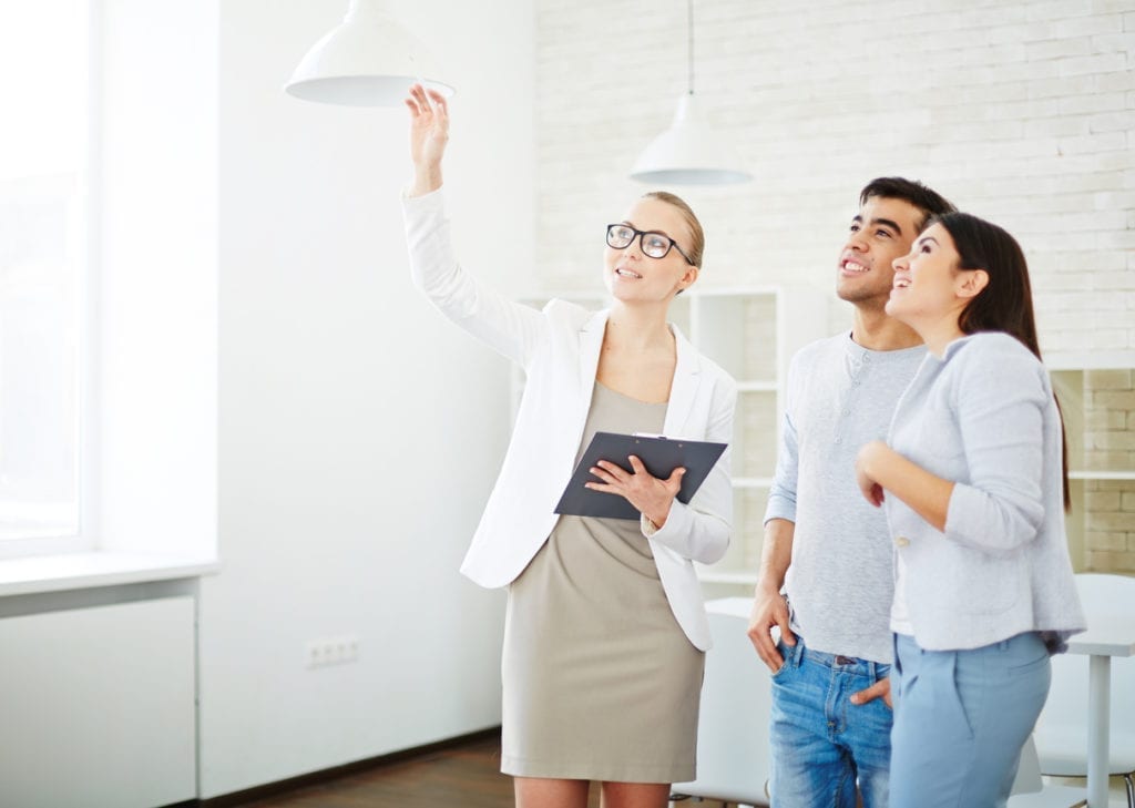 Female realtor showing one of rooms to young couple